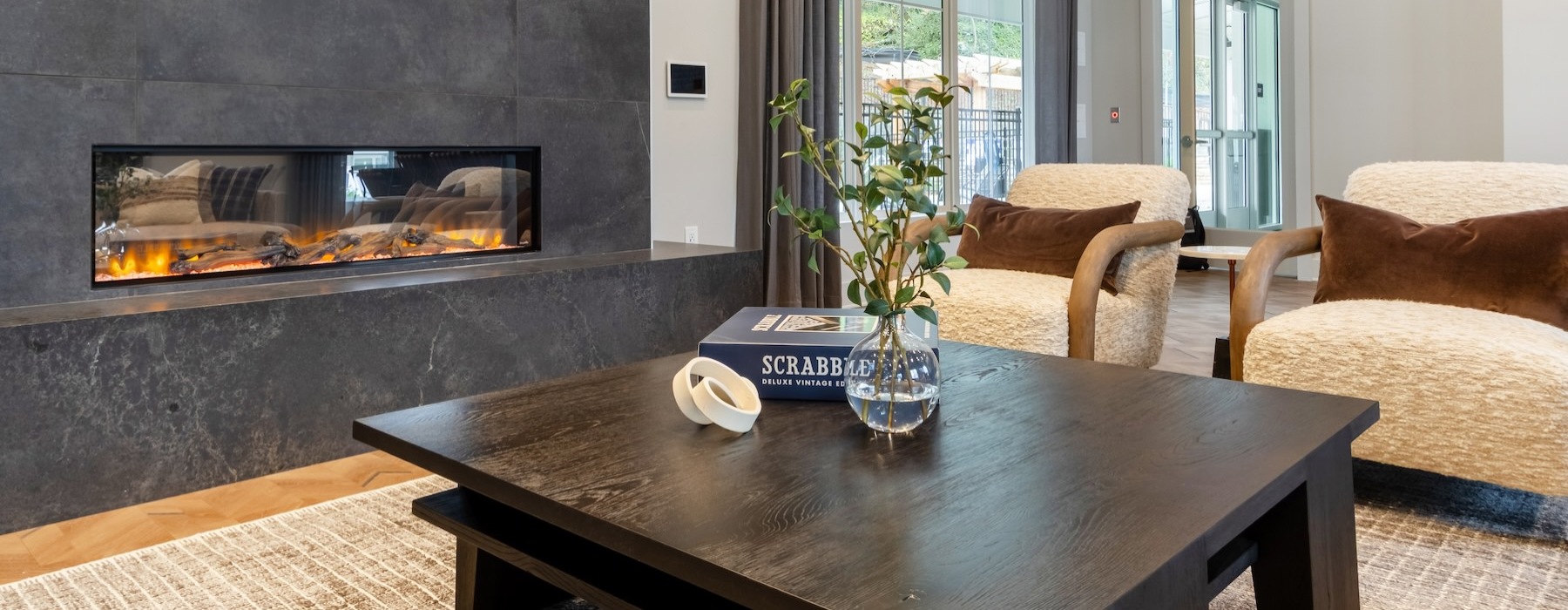 a lounge with a fireplace, chairs and a table
