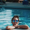 a woman smiling in a pool wearing sunglasses